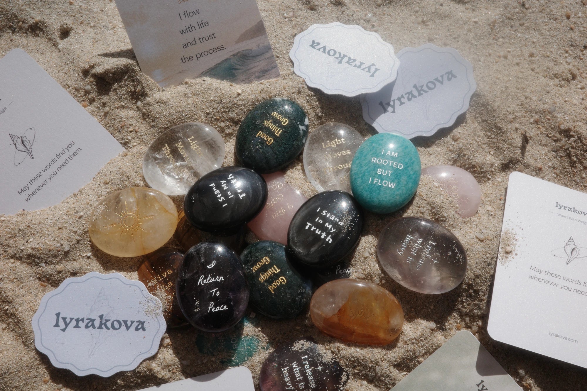 Engraved lyrakova crystals, blessing cards and shell stickers on beach sand